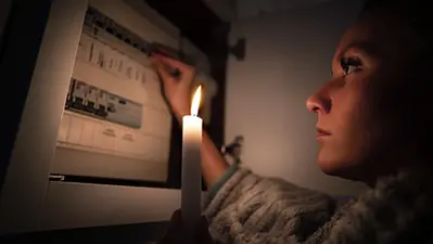 Kvinna med ljus framför proppskåp_NS energiberedskap.webp